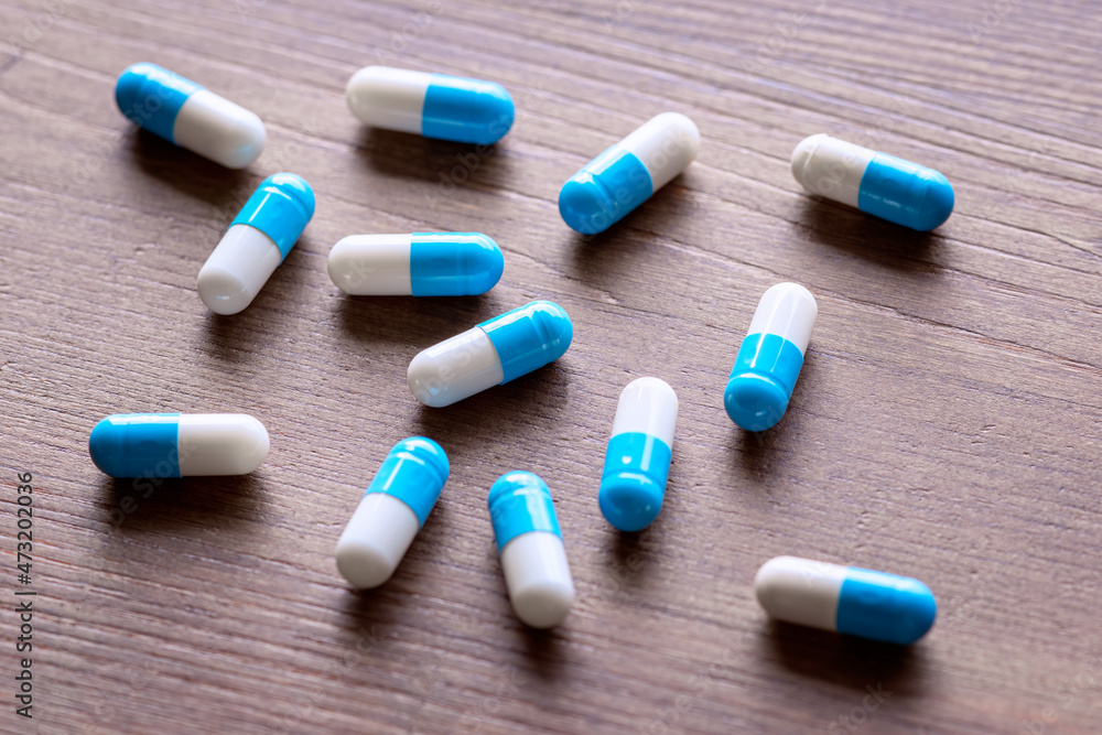 Close up of colorful pills. Two-tone drugs and supplements. Capsules to be swallowed wrapped in the blister. Three tablets out of the blister. Close up of colorful pills. Two-tone drugs and supplements. Capsules to be swallowed wrapped in the blister. Three tablets out of the blister.