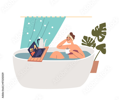 Young girl take bath watching video or movie on laptop drinking hot tea or cocoa