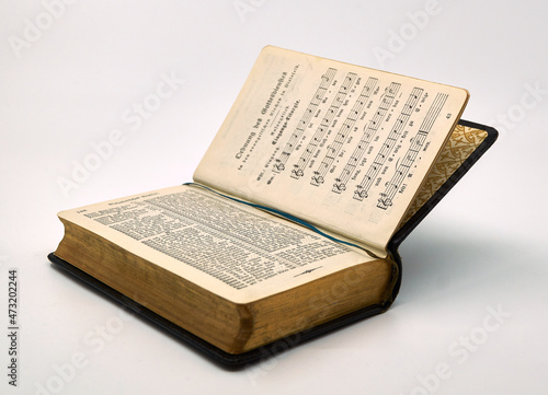 Old open hymnbook in German with gilded edge isolated on a white background                              photo