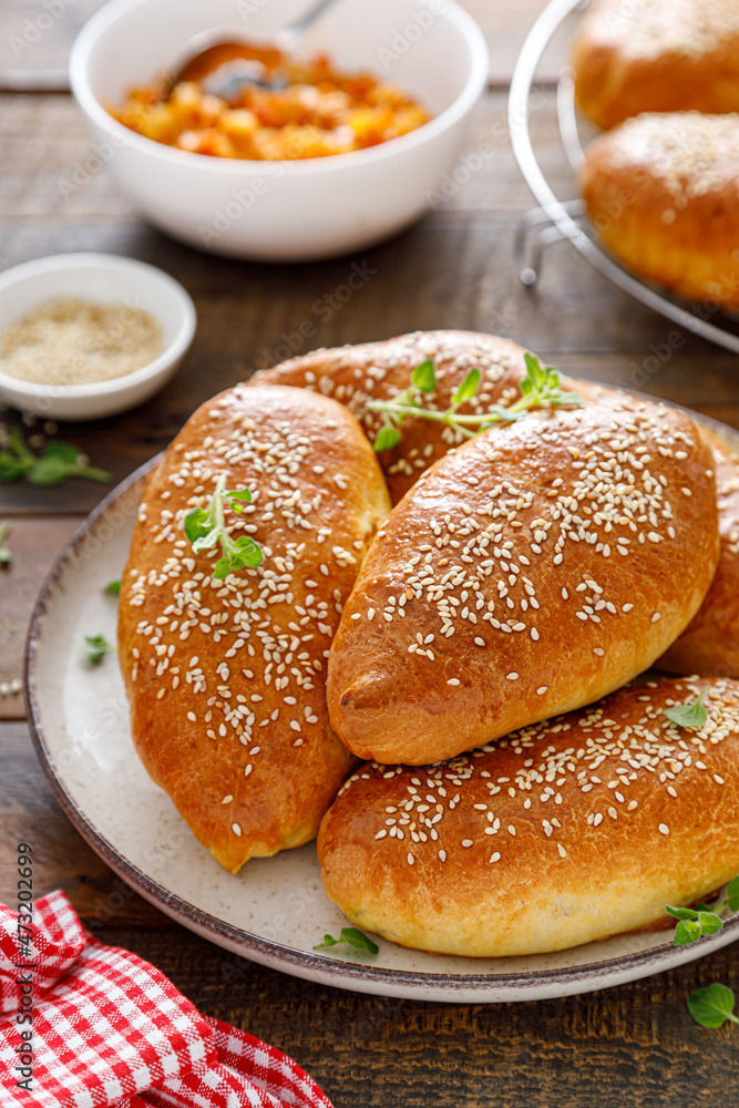 Homemade baked pies or patties stuffed with cabbage on wooden background Homemade baked pies or patties stuffed with cabbage on wooden background