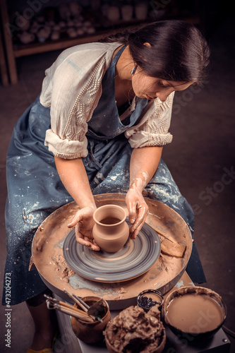 Beautiful young woman master demonstrates the process of making ceramic dishes using the old technology. Handwork. photo
