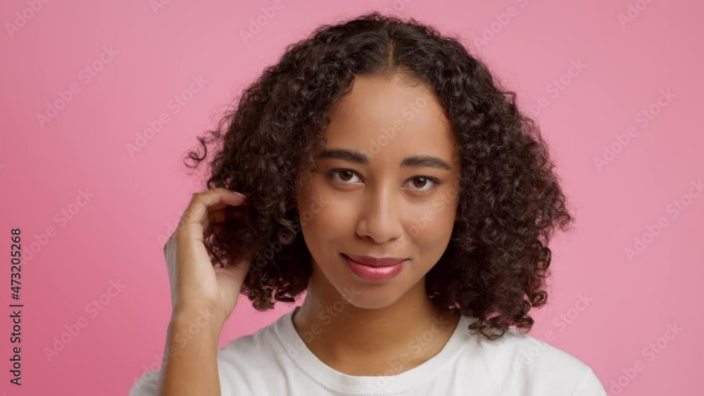 African American Woman Twisting Curl On Finger Over Pink Background African American Woman Twisting Curl On Finger Over Pink Background