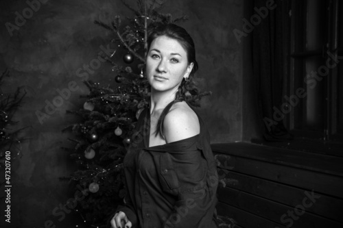 Woman in pajamas near Christmas tree and gifts. Dark blue concept. © Yekatseryna