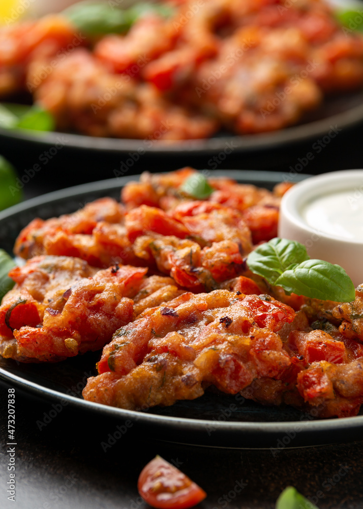 Greek tomato fritters, tomatokeftedes served with yogurt on plate. Greek tomato fritters, tomatokeftedes served with yogurt on plate.