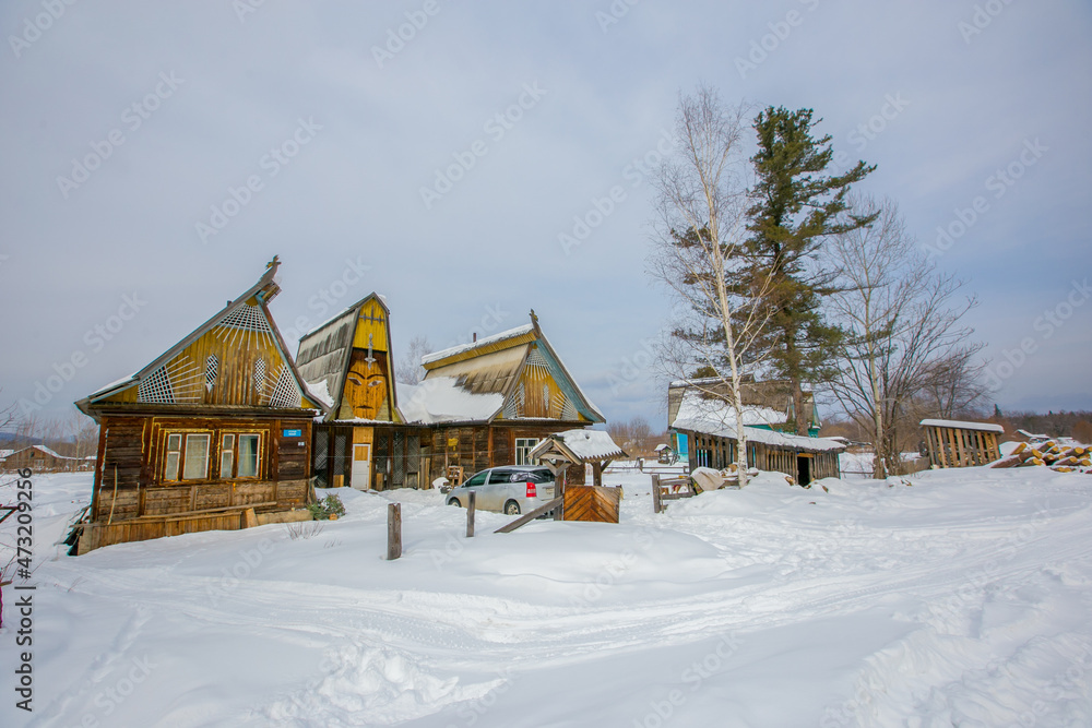 The winter village of Krasny Yar of the small indigenous peoples of the north of Russia - the Udege. Street in the village in winter. Wooden Russian huts in a beautiful village.