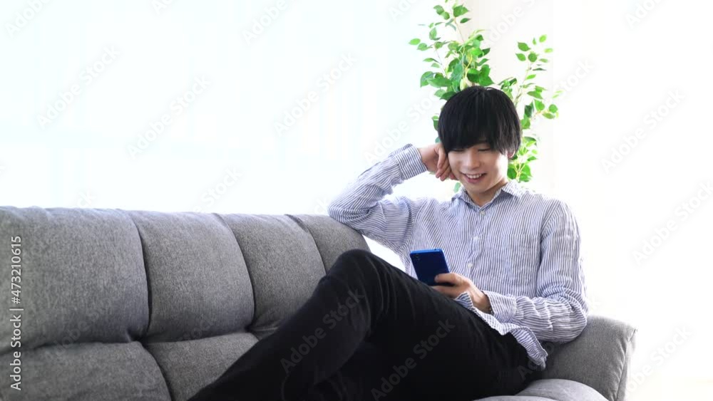 リビングで寛ぐ男性 スマートフォン リビングで寛ぐ男性 スマートフォン