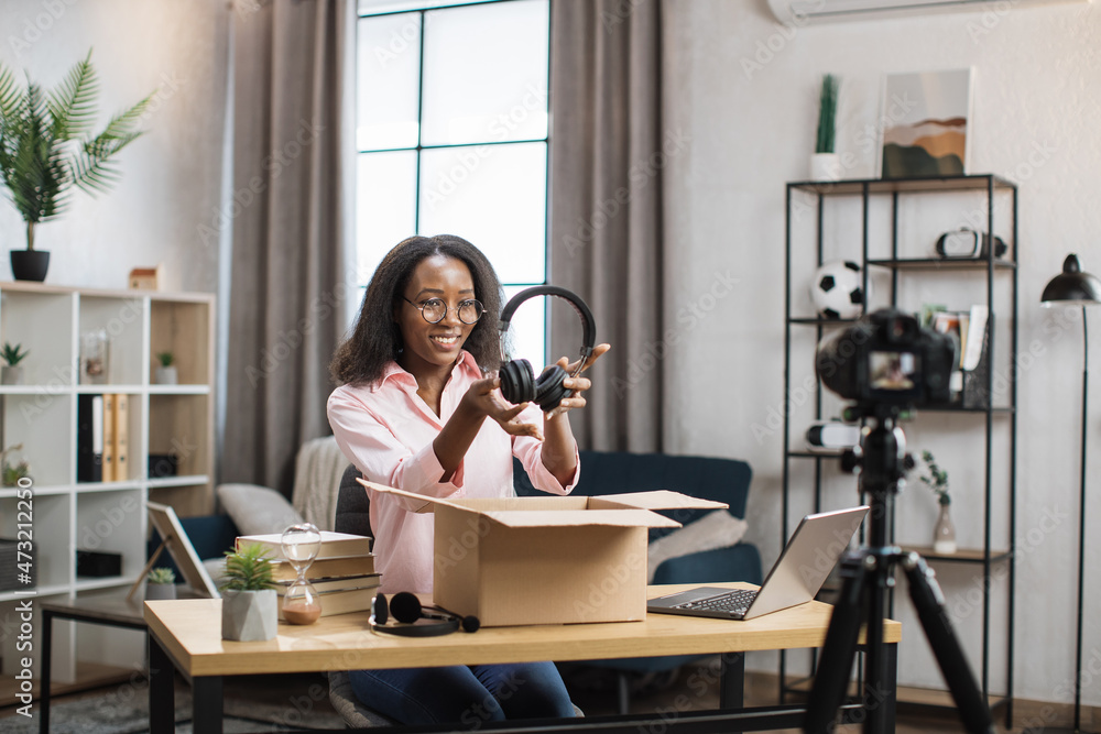 African american woman recording video on camera while unpacking box ...