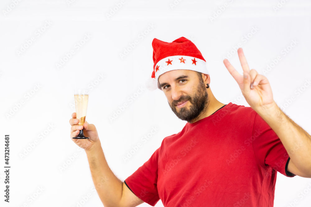 Young very happy Caucasian man with red Christmas hat toasting with a glass of champagne on a white background, dressed in a red shirt Young very happy Caucasian man with red Christmas hat toasting with a glass of champagne on a white background, dressed in a red shirt