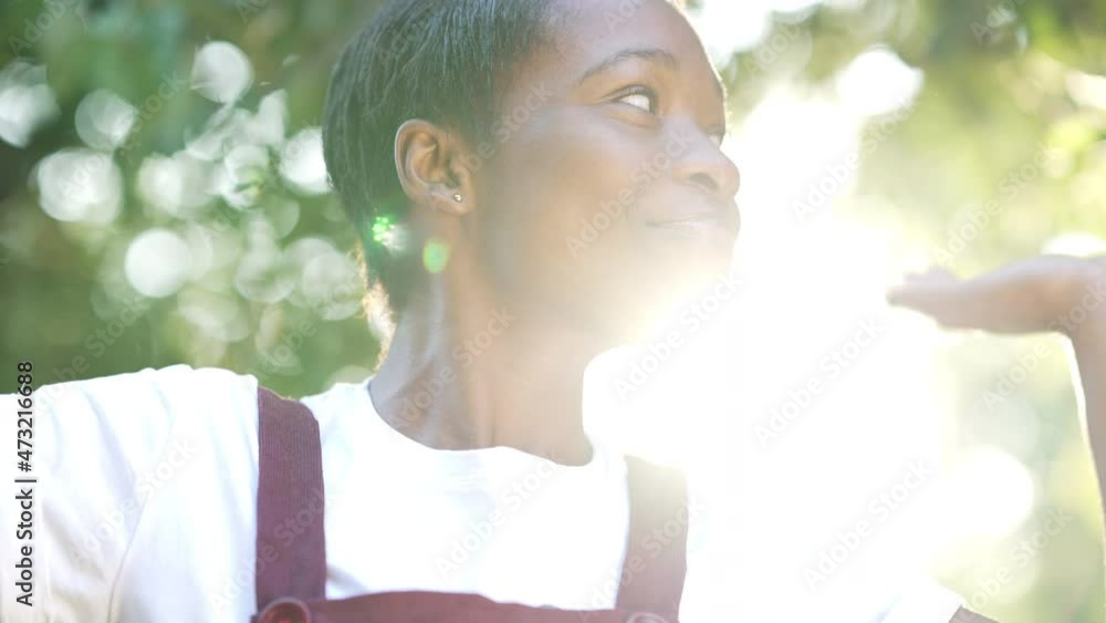 Close-up happy carefree African American slim woman dancing in sunrays outdoors. Portrait of smiling cheerful young lady enjoying summer weekend leisure. Lifestyle and happiness Close-up happy carefree African American slim woman dancing in sunrays outdoors. Portrait of smiling cheerful young lady enjoying summer weekend leisure. Lifestyle and happiness