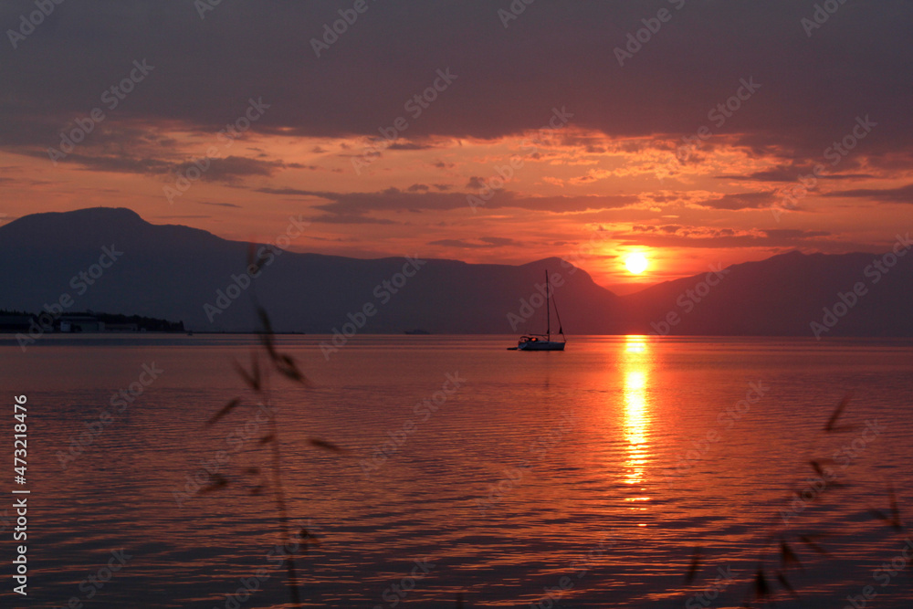 Scenic sunset and a lonely sailboat at the coast of Trogir