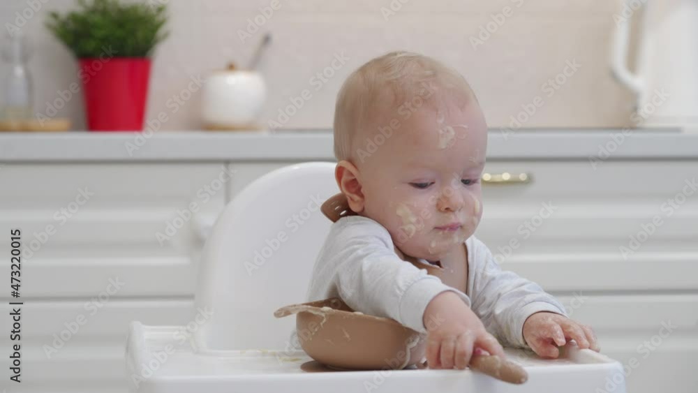 Child eats porridge, toddler learning to eat with a spoon, smiling kid with food stained face. High quality 4k footage Child eats porridge, toddler learning to eat with a spoon, smiling kid with food stained face. High quality 4k footage