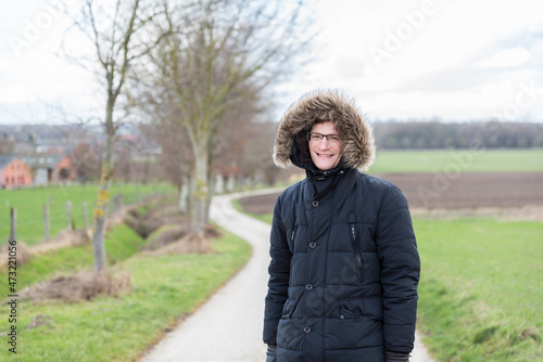 Active forty year old man in a large winter coat with cap posing on a walking trail in Hageland, Flanders, Belgium photo