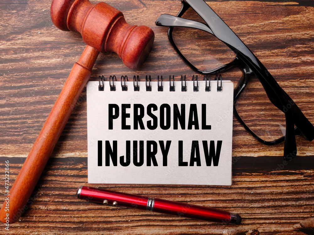 Gavel,pen,glasses and notebook written with text PERSONAL INJURY LAW on a wooden background. Gavel,pen,glasses and notebook written with text PERSONAL INJURY LAW on a wooden background.