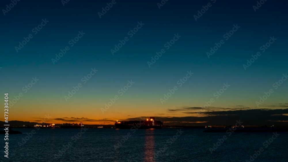 Sunrise at a shipping harbor with container ships waiting to be offloaded during the global supply chain shipping crisis - wide angle time lapse Sunrise at a shipping harbor with container ships waiting to be offloaded during the global supply chain shipping crisis - wide angle time lapse