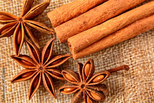 heap of star anise and group sticks of cinnamon close up on canvas fabric