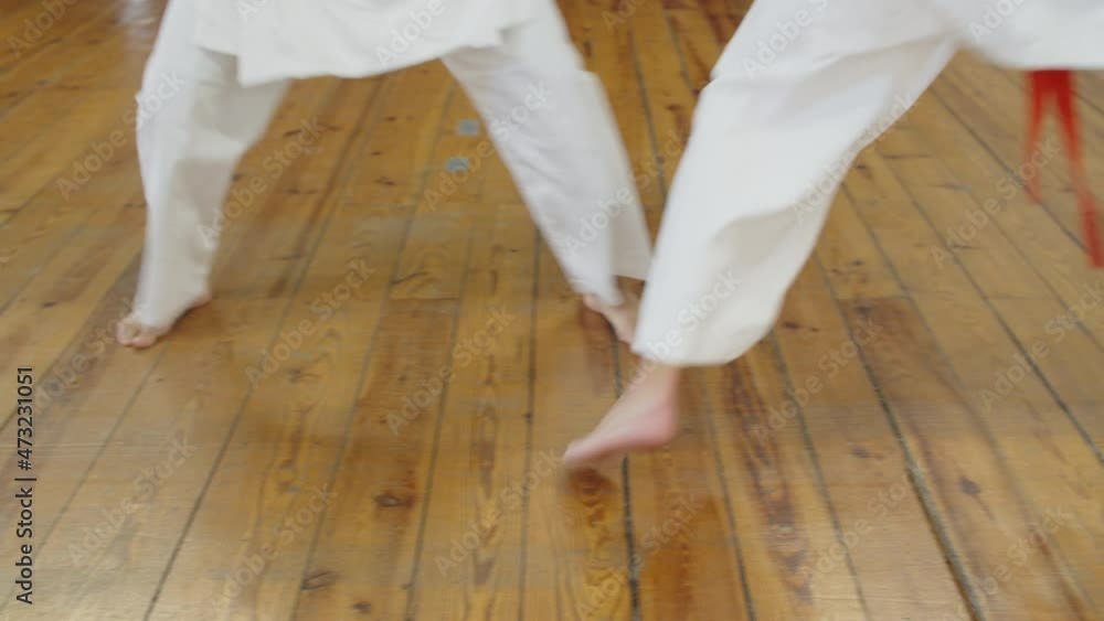 Close-up shot of karatekas legs fighting in gym. Handheld shot of unrecognisable girls in white kimonos practicing karate, preparing for competition, improving skills. Martial arts, sport concept Close-up shot of karatekas legs fighting in gym. Handheld shot of unrecognisable girls in white kimonos practicing karate, preparing for competition, improving skills. Martial arts, sport concept