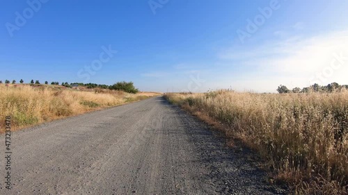 C. Titanio - a dirt road to Guillena on a summer landscape, Salteras, province of Seville, Andalusia, Spain - dolly move forward photo