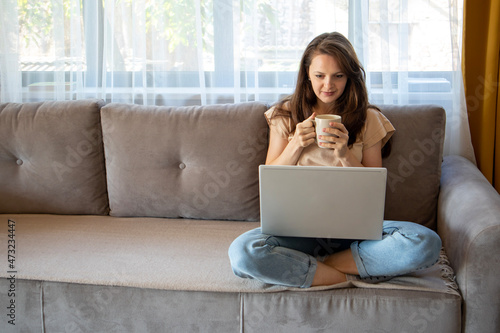 A young woman is drinking a cup of coffee during working from home.