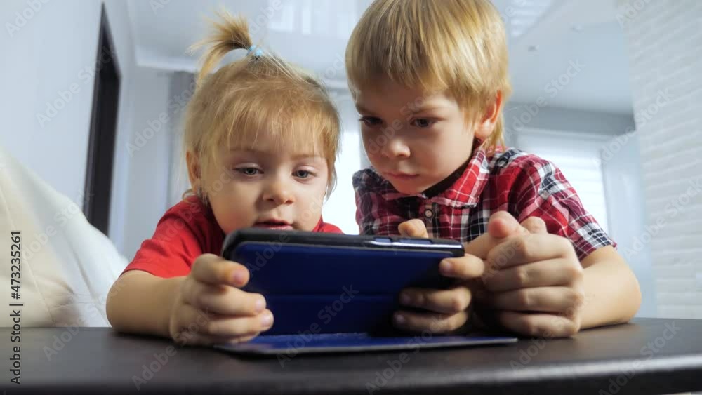 children watch online video cartoons on a smartphone. kids lifestyle little boy and girl brother sister watch online streaming broadcasting on the phone children watch online video cartoons on a smartphone. kids lifestyle little boy and girl brother sister watch online streaming broadcasting on the phone