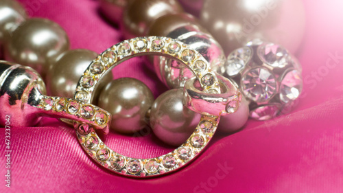 Bracelet made of beads and rhinestones on a pink background