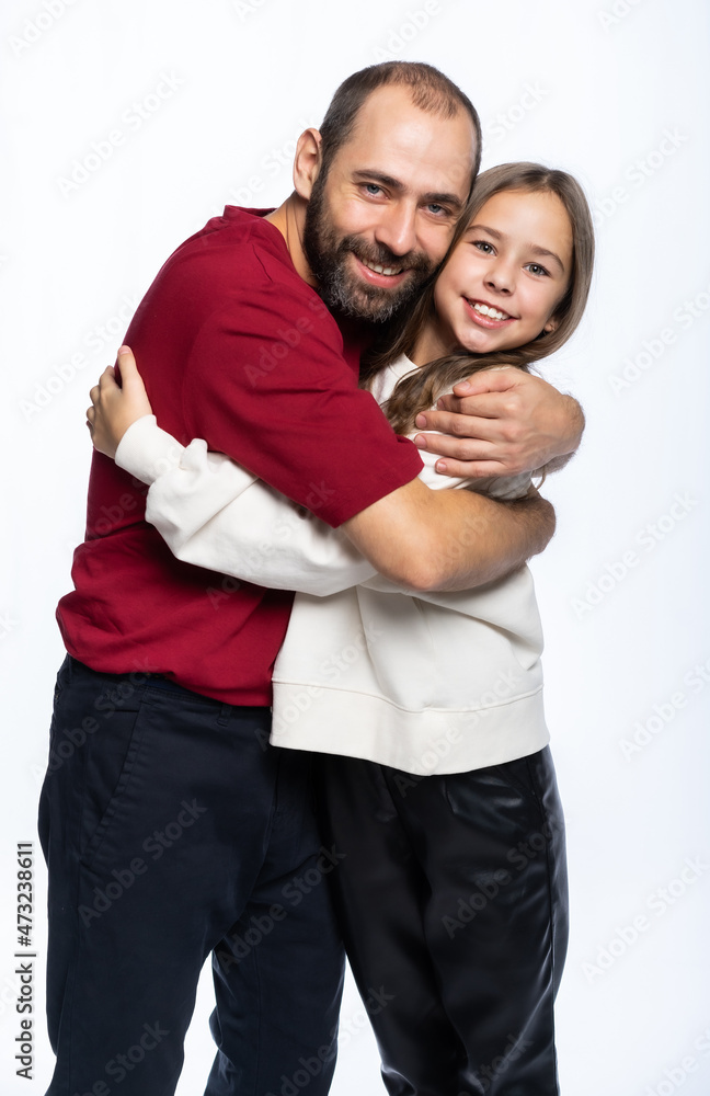 dad hugs daughter by the shoulders in the studio. a man in a burgundy-red T-shirt, a girl in a white sweatshirt. isolated white background dad hugs daughter by the shoulders in the studio. a man in a burgundy-red T-shirt, a girl in a white sweatshirt. isolated white background