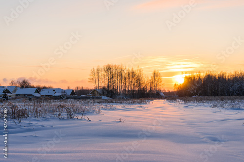 Sunrise on a winter field close to village