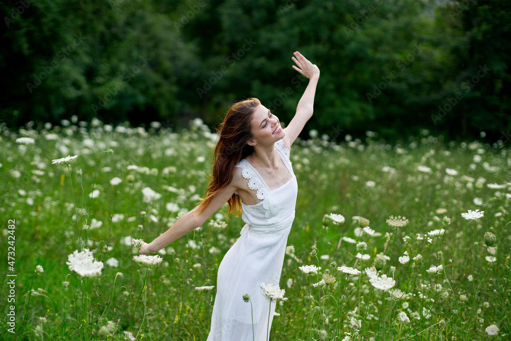 cheerful woman in a field with flowers in a white dress in nature cheerful woman in a field with flowers in a white dress in nature