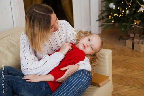 family on Christmas holidays together at home. mom and little daughter hug and play at home on Christmas Day