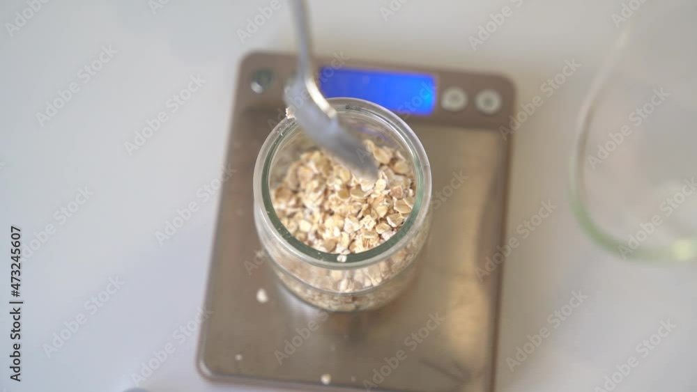 Pouring oats into a jar to be weighed for creating artisanal hand soaps, Top view close up handheld shot Pouring oats into a jar to be weighed for creating artisanal hand soaps, Top view close up handheld shot