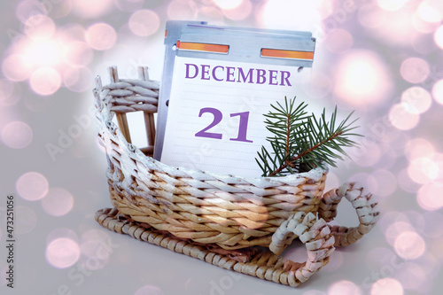 Calendar for December 21  leaves of a calendar with the name of the month  number 21 in a decorative sleigh  a fir branch on a light background  close-up