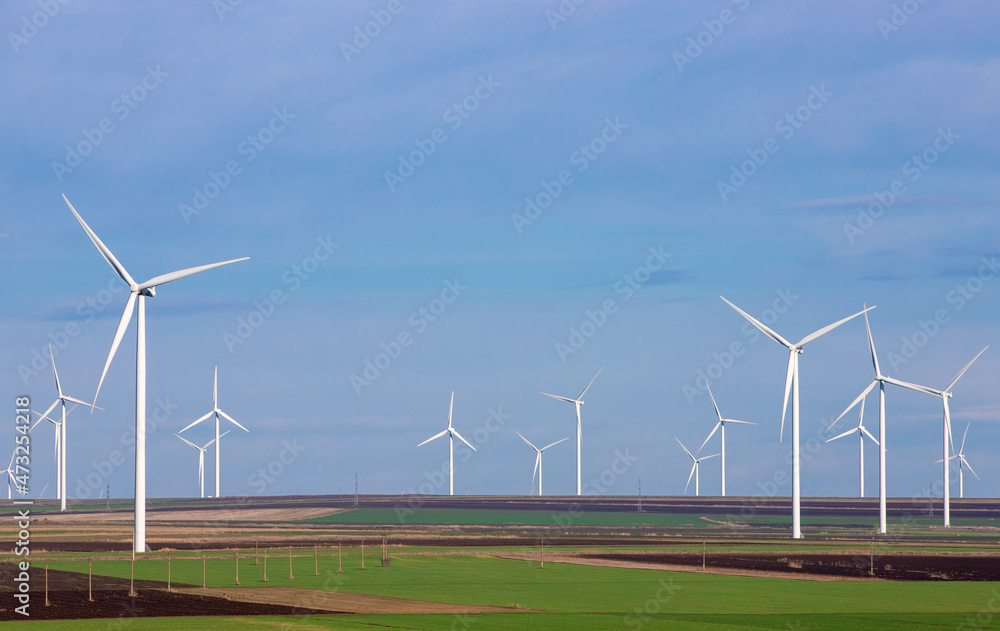 Eolian farm renewable energy on a field against blue sky Eolian farm renewable energy on a field against blue sky