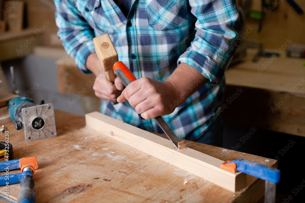  A carpenter in a plaid shirt works a workshop. Wood. Ecological compatibility. Lifestyle. Close up.