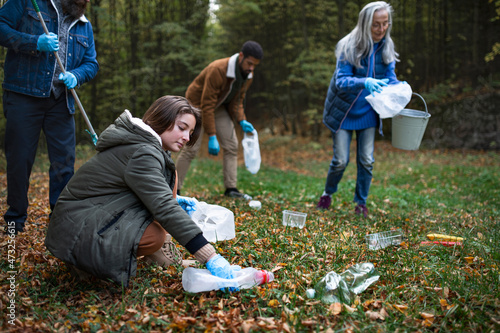 Obraz na plátně Group of volunteers cleaning up forest from waste, community service concept