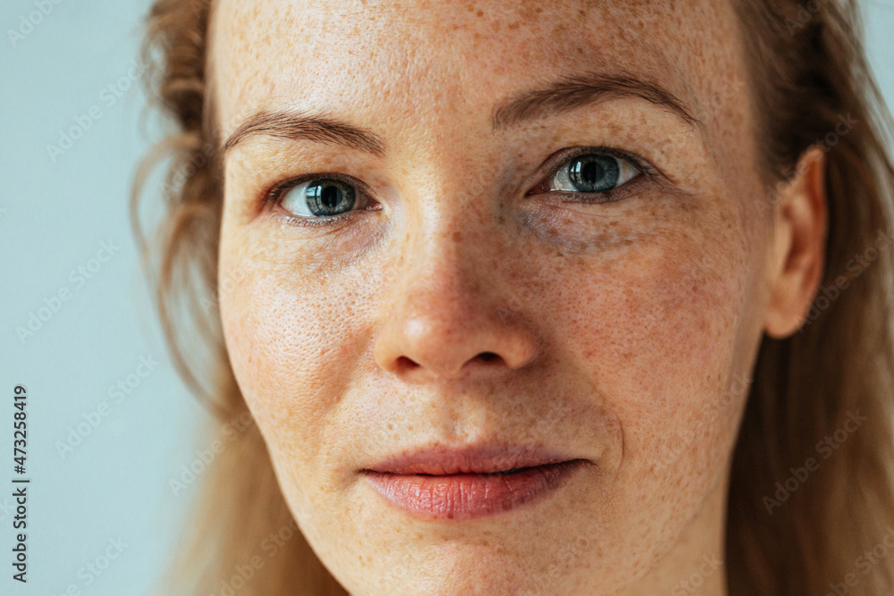 Fototapeta premium Beautiful woman with read hair and freckles. Close up portrait against black background