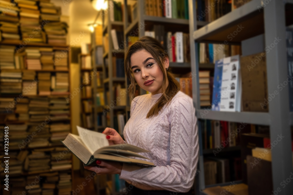 portrait of young female student or teacher near books in the library portrait of young female student or teacher near books in the library
