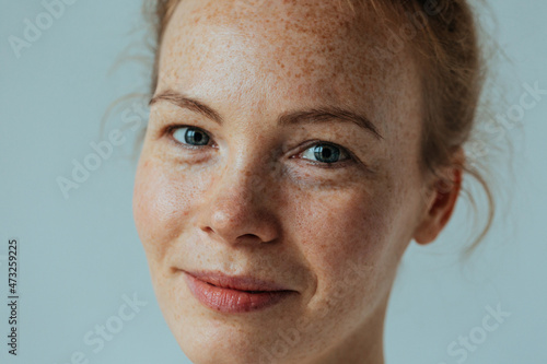 Beautiful woman with read hair and freckles. Close up portrait against black background