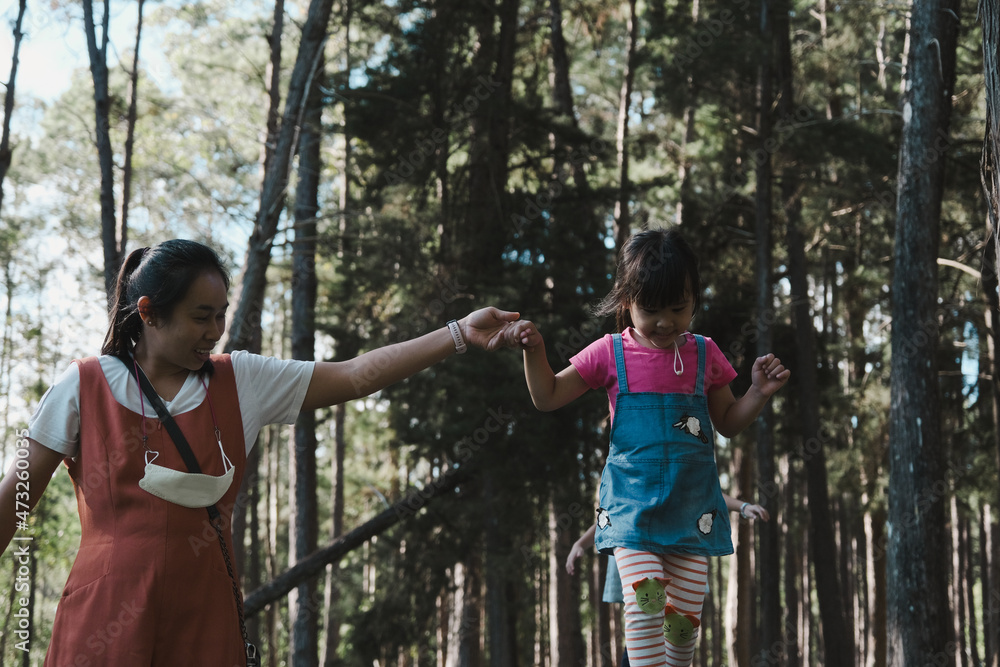 Young mother helping her daughter walking on a log in the park. child on the balance beam. Play is learning in childhood. Young mother helping her daughter walking on a log in the park. child on the balance beam. Play is learning in childhood.