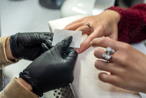 gorgeous manicure master in special black gloves works on the girl's nails.