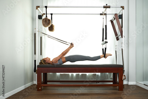 Tela The instructor does exercises on the reformer, a beautiful girl trains on the modern reformer simulator to work out deep muscles, the modernized reformer equipment for Pilates and yoga