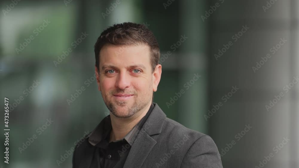 confident beared businessman stands in front of the office building, looking at camera smiles Portrait of successful businessman confident beared businessman stands in front of the office building, looking at camera smiles Portrait of successful businessman