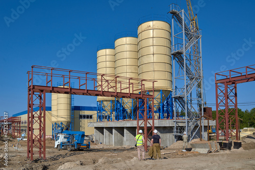 workers at a construction site against the background of tanks
