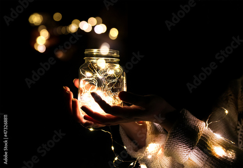 Hands holding a jar with a garland and a bokeh