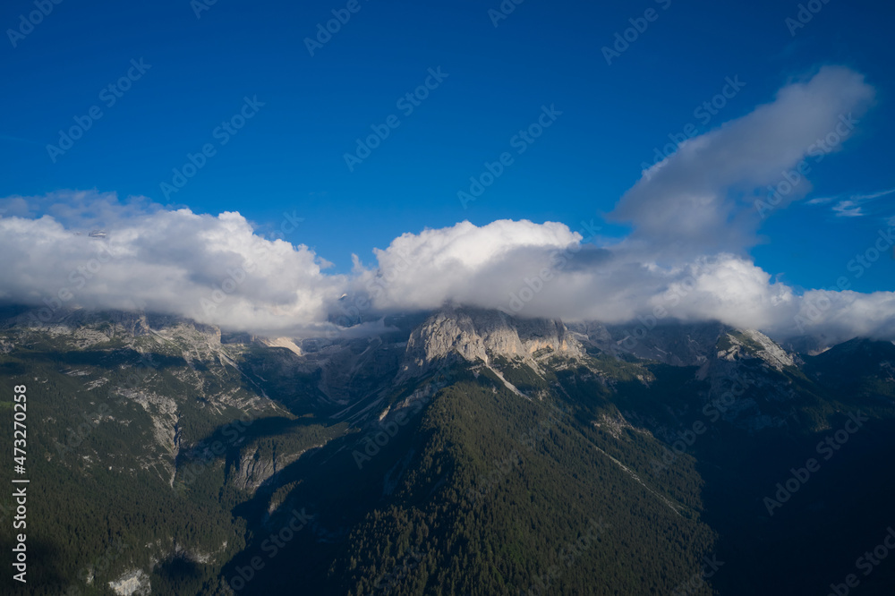 Idyllic landscape in the Alps. Panorama of beautiful countryside of Italy. Clouds on top of the Alps, blue sky. High mountains in the Europe.