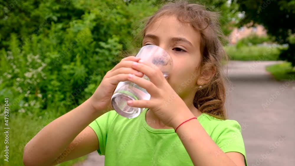 The child drinks water from a glass. Selective focus. The child drinks water from a glass. Selective focus.
