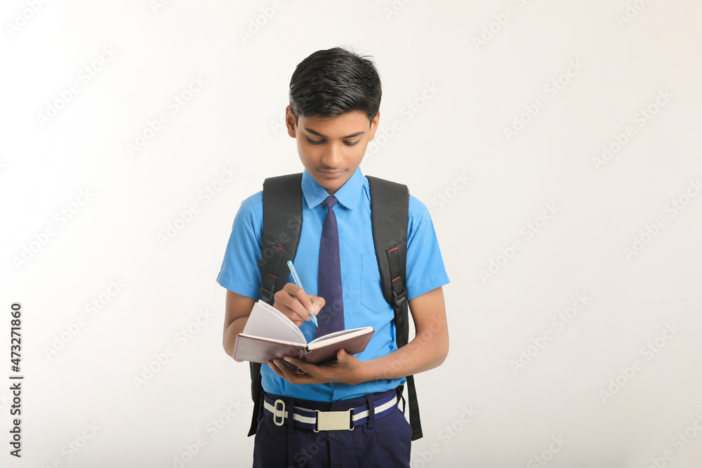 Indian school boy in uniform and holding diary in hand on white background. Indian school boy in uniform and holding diary in hand on white background.