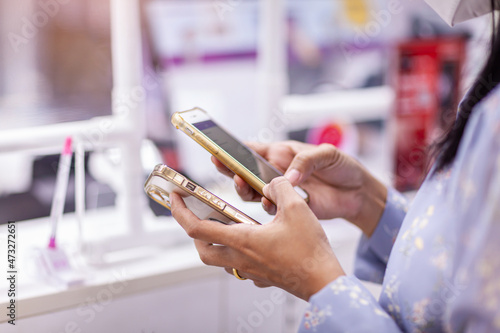 Woman shopping in supermarket background. Close up view girl buy products using digital gadget in store. Hipster at grocery using smartphone. Person comparing the price of produce