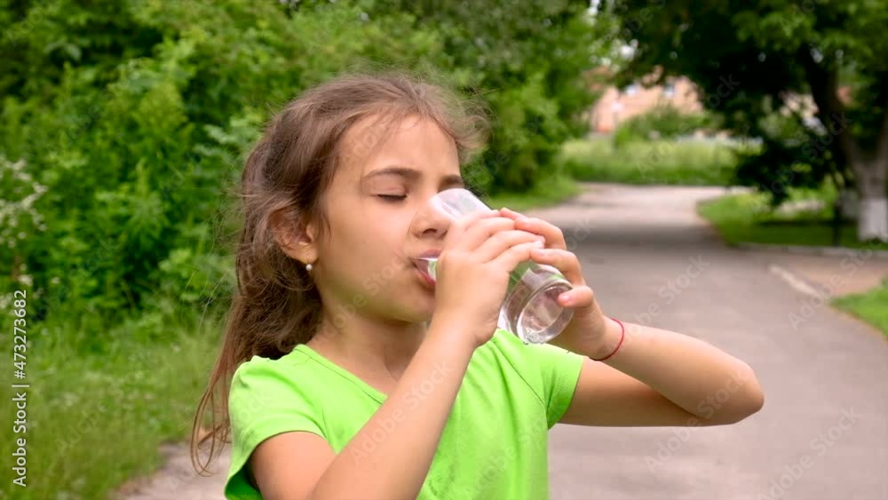 The child drinks water from a glass. Selective focus. The child drinks water from a glass. Selective focus.