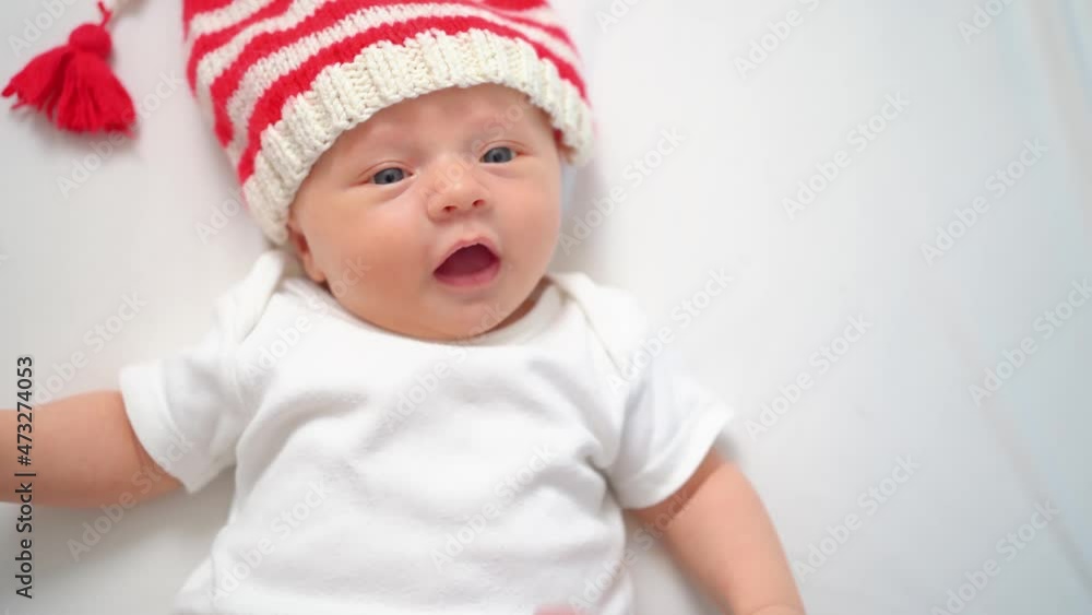 hand touches face of cute little kid in cap of Christmas elf or gnome.baby santa hand touches face of cute little kid in cap of Christmas elf or gnome.baby santa