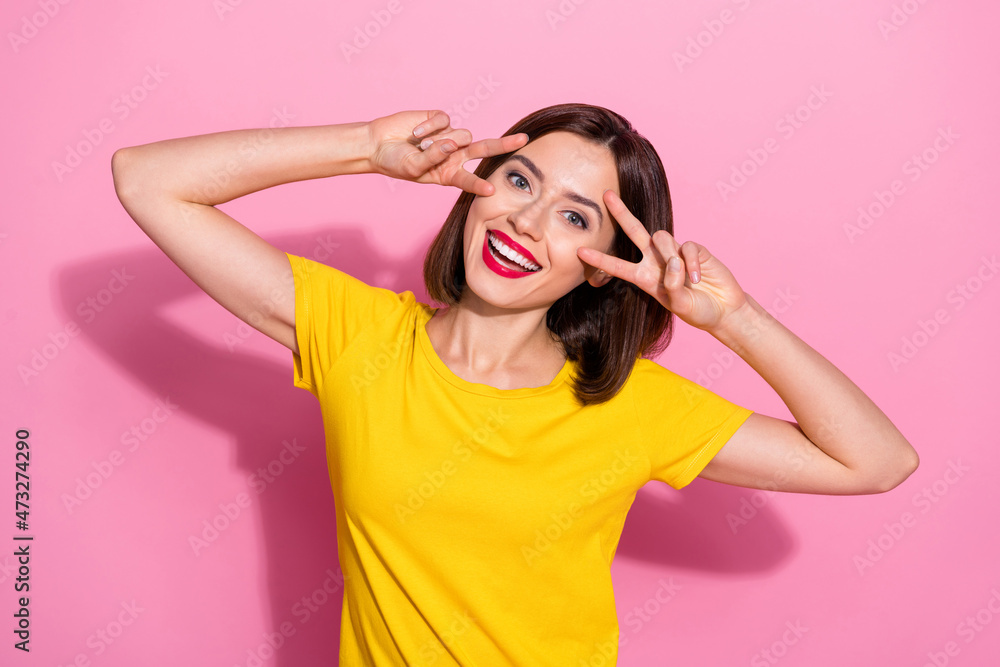 Photo of pretty sweet young lady dressed yellow clothes smiling showing two v-signs cover eyes isolated pink color background Photo of pretty sweet young lady dressed yellow clothes smiling showing two v-signs cover eyes isolated pink color background