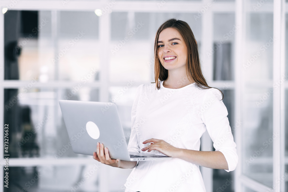 Smiling young business woman in white shirt posing while holding Smiling young business woman in white shirt posing while holding